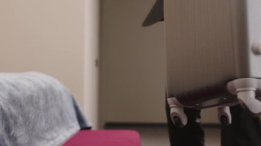 Resmi kıyafet içinde tanınmayan bir iş adamının modern otel odasında bavulunu yatağın yakınındaki bir bankete yerleştirirken görüntüsü.