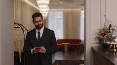 Orta sınıf başarılı Orta Doğulu iş adamının resmi. Otel lobisinde akıllı telefon kullanarak.