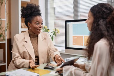 Siyahi bir kadının iş konuşurken orta boy portresi ve geniş bir gülümseme. Ofisteki çalışma masasında çalışan kadın patronu olan çeşitli takımlar, kopyalama alanı