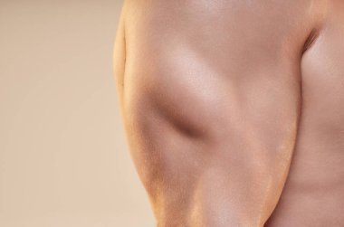 Stüdyoda pompalı pazılara ve güçlü adamlardan oluşan trisepslere yaklaş. Sağlıklı atletik kasların detaylı çekimi, temiz kılsız deri dokusu nötr arkaplanda, kopyalama alanı