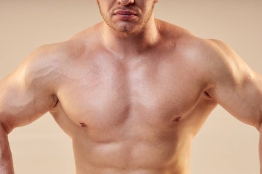 Erkek vücut geliştiricinin öne doğru poz verirken kesilen görüntüsü. Sporcunun çıplak kaslı göğsü nötr arkaplanda izole edilmiş, boşluğu kopyala