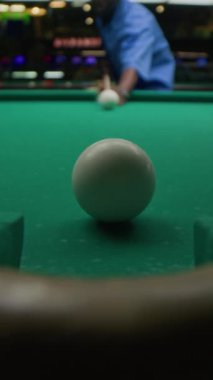 Pub 'da oynanan bilardo topunu hedef alan konsantre olmuş genç siyahi adamın dikey bıçak atışı.