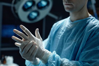 Cerrahın koruyucu eldiven giyip fotokopi odasında ameliyata hazırlandığı görüntüler.