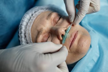 Ameliyat masasında yatan hastaya oksijen tüpünü ayarlayan cerrahın üst görüntüsü.