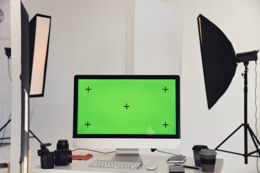 Profesyonel ışıklandırma ekipmanlarıyla iş yerindeki çalışma masasında krom tuşlu yeşil ekranlı bilgisayarın minimal arkaplan görüntüsü, kopyalama alanı 