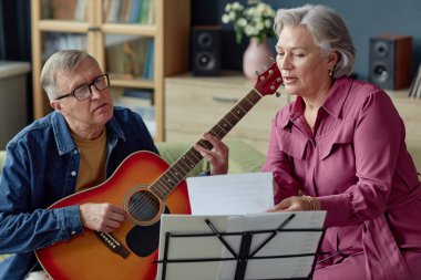 Evde birlikte şarkı söyleyip müzik yapan yaratıcı hobilerin ön plandaki portresi.