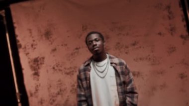 Benekli kırmızı arka planda poz veren kendine güvenen Afro-Amerikan adam stüdyo fotoğrafı çektirirken...