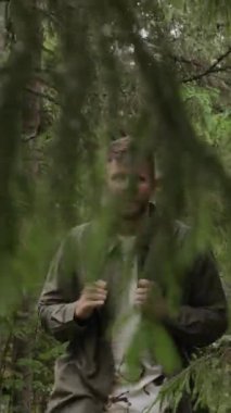 Kafkasyalı bir adamın gündüz vakti ormanda yürürken sırtında sırt çantası taşıdığı orta boy bir fotoğraf.