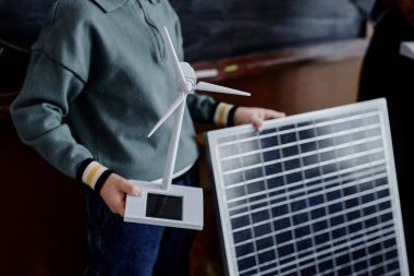 Mini güneş enerjisi türbinine yakın durun ve büyük güneş paneli ilkokul öğrencisinin elinde sınıfta sürdürülebilir teknoloji hakkında sunum yapan, kopyalama alanı