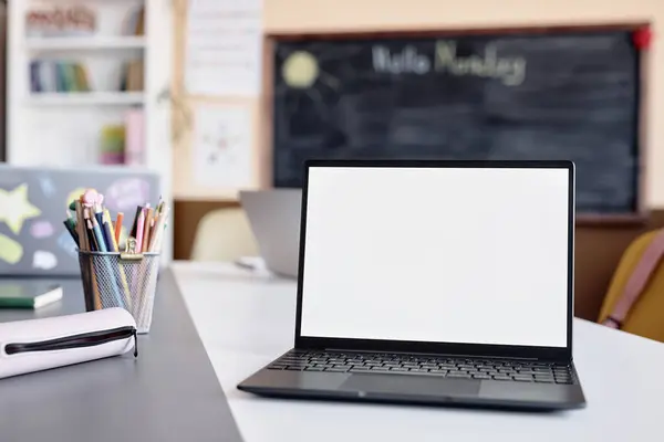 stock image Background shot of laptop empty mockup screen on table in front of camera in primary school classroom, copy space