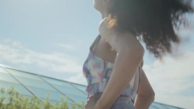 Genç kıvırcık saçlı erkek ve kadın, güneşli bir günde açık havada durup antrenmandan önce ısınma egzersizleri yapıyorlar.