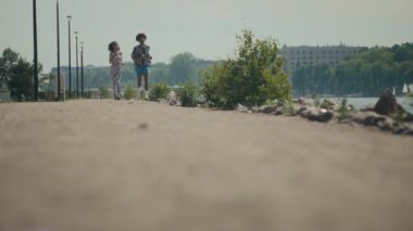 Spor giyimli genç bir çiftin şehrin asfaltsız yolundaki kameraya doğru koşarken çekilen zemin seviyesi.