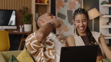 Gündüz vakti parlak oturma odasında kanepede otururken birbirlerini gıdıklayan şakacı çiftlerin orta boy fotoğrafı.