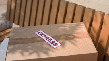 Açık havada gün ışığında ahşap bankta bırakılan karton kutunun orta derecede kapatılması, insan yok.