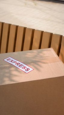 Dışarıdaki ahşap bankta ekspres teslimat etiketli karton kutuda dikey bir karton resim.