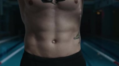 Kolları ve vücut dövmeleri olan, yüzme gözlüğü takan, kapalı alanda antrenman için hazırlanan, atletik, genç, beyaz bir adamın fotoğrafını çek.