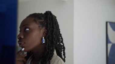 Odaklanmış Afrikalı Amerikalı bir kadının galerideki sanat eserlerine, arka planda sergilenen genç bir adamın görüntüsüne yakından bakın.