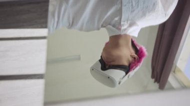 Modern sanat galerisinde aynalı masanın yanında duran pembe saçlı Z jeneratörünün görüntüsünü yukarı kaldır. Arttırılmış gerçeklikte üç boyutlu gezintiyi deneyimlerken havada süzül.