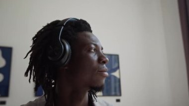 Çoklu etnik galeri ziyaretçileri kablosuz kulaklıklarla müzik rehberini dinliyor ve sergi salonunda modern sanat eserlerini inceliyorlar.
