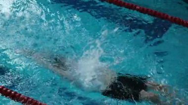 Kafkasyalı sporcunun havuzda yüzme tekniğini kullanarak havuz başında yarışırken yavaş çekimleri.