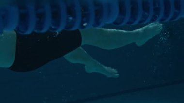 Tanımlanamayan erkek yüzücü bacakları su altında yüzme tekniği uyguluyor.