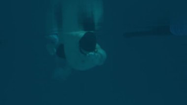 Yüzme gözlükleri takan ve havuzda yüzme antrenmanı yapan beyaz adamın yavaş çekimi.