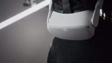 Sanal gerçeklikteki kavramsal sanat sergisini keşfederken, titreyen ışıkla karanlık galeri salonunda duran ve etrafa bakan, VR kulaklıklı genç Afrikalı Amerikalı bir adam.