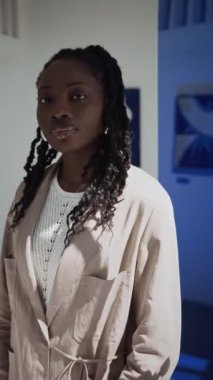 Siyahi bir kadının sergi salonundaki konsept sanat galerisinde kameraya poz verirken dikey çekimi.