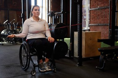 Spor salonundaki egzersiz makinelerini kullanarak engelli aktif bir kadının tam boy portresi