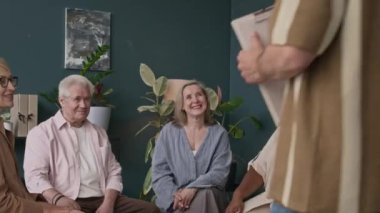 Kafkasyalı erkek uzmanla grup terapisine giderken modern ofiste daireler çizerek oturan etnik çeşitlilikte erkek ve kadın yaşlıların orta boy fotoğrafları.