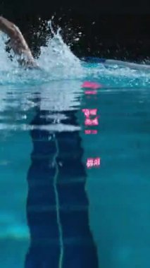 Yüzme gözlüğü takan ve kapalı havuzda yarışı bitirdikten sonra kameraya bakan Kafkas atletik genç adamın dikey Slowmo portresi