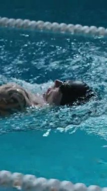 Kafkas sporcusunun havuz suyunda yüzerken yavaş çekilen dikey görüntüsü.