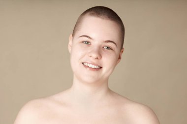 Gülümseyen, kısa saçlı ve makyajsız genç bir kadının, tarafsız arkaplan fotokopi alanındaki kameraya bakışının minimum portresi.