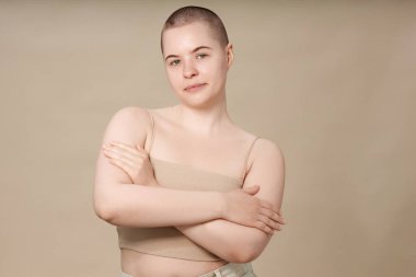 Makyajsız gülümseyen genç kızın minimum bel altı portresi stüdyo fotokopi alanındaki tarafsız arka planda kendine güvenle duruyor.