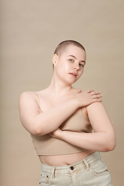 Minimal portrait of young girl with short hair posing elegantly on neutral background in studio