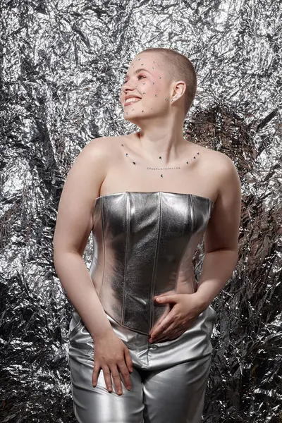 stock image Vertical fashion portrait of young woman wearing silver outfit posing with smile over metallic background