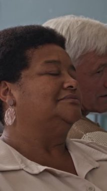 Emekliler yurdunda psikolojik grup çalışması yapan, sırt sırta oturup birbirlerine tek tek bilgi aktaran çeşitli yaşlı insanların dikey göğsü.