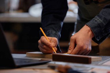 Çalışma alanındaki dizüstü bilgisayarın yanına yerleştirilen not defterine el yazısı ve çizimler, iyi aydınlatılmış ortamdaki yaratıcılık ve işçiliğe odaklanıyor