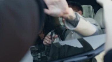Zarif gri takım elbiseli beyaz adam, limuzininin arka koltuğunda güzel bir çift ırklı kız arkadaşıyla otururken elinde paparazzi fotoğraflarının ve fotoğraf makinelerinin görüntülerini engelliyor.