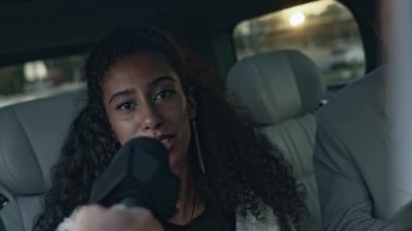 Zarif gri takım elbiseli beyaz erkek arkadaşıyla limuzinin arka koltuğunda giderken mikrofonla paparazzilerin sorularını cevaplayan çekici, Melez genç kızın sandığı.