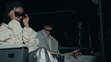 Çekici genç melez kadın ünlü paparazzilerden kaçmak ve gece vakti pahalı siyah arabadan çıkmak için siyah güneş gözlüğü takıyor.