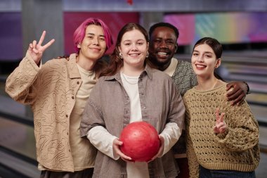 Bovling salonunda gülümseyen ve bowling topu tutan çeşitli grupların portresi mutlu anılar yaratıyor.