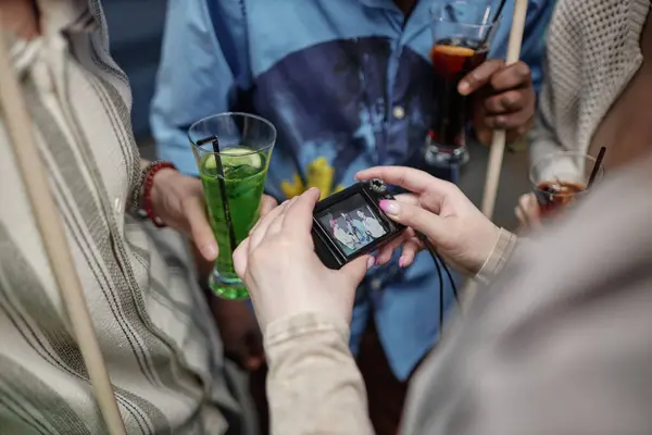 stock image Group of people socializing, holding drinks while someone is taking a picture with a compact digital camera during gathering