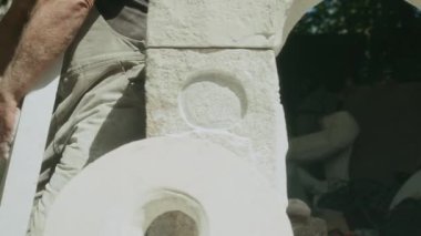 Profesyonel erkek heykeltraşın orta boy porselen taş parçaları taşırken bahçede el işi yaparken çekilmiş bir fotoğrafı.