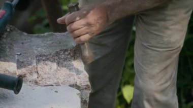 Çekiç ve keski kullanan tanınmayan profesyonel zanaatkârın yavaş çekimleri açık havada doğal taşları oyuyor.