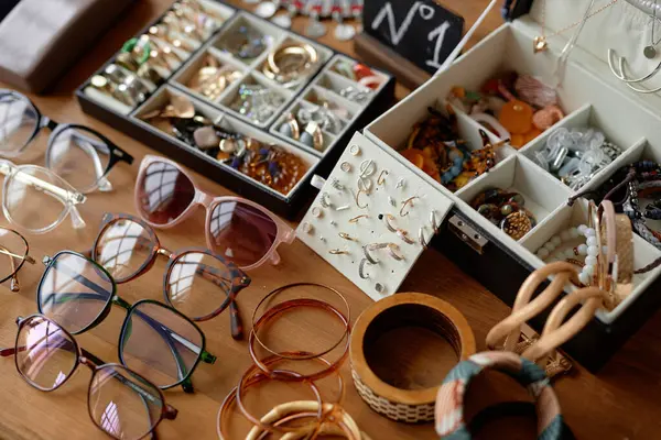 stock image Close up on vintage sunglasses, unique rings and earrings displayed on table at thrift store