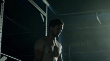 Spor salonunda ısınırken omuz ve kol rotasyonları yapan formalı beyaz bir adamın orta boy fotoğrafı.