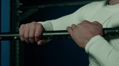 Tanınmayan erkek sporcu ya da jimnastikçinin karanlık spor arka planında metal bara tutunması.