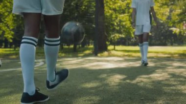 Genç Afrikalı Amerikalı futbolcunun, güneşli bir günde sahada oynarken, takım arkadaşını selamlarken ve topunu ayaklarıyla hokkabazlık yaparken yavaş çekim yapın.