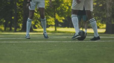 Spor ayakkabı ve uzun beyaz çoraplar giyen iki tanınmayan gencin yaz mevsiminde çimenlikte futbol oynaması.